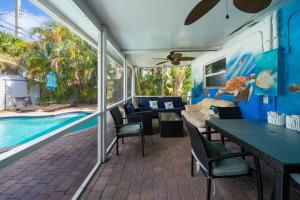een patio met een tafel en stoelen en een zwembad bij Palm Paradise-Seaside Home w Heated Saltwater Pool in Fort Lauderdale