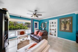 een woonkamer met een bank en een plafondventilator bij Palm Paradise-Seaside Home w Heated Saltwater Pool in Fort Lauderdale