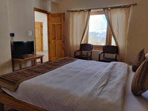 a bedroom with a large bed and a television at Kazdar Villa in Leh