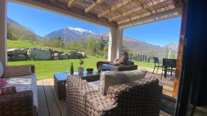 a woman sitting on a patio with a view of mountains at Le Chalet de Castille - chalet pyrénéen grand confort - spa in Beaucens