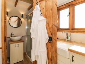 a bathroom with a shower and a white robe hanging on a door at Buzzards in Crediton
