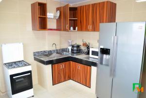 a kitchen with wooden cabinets and a white refrigerator at RESIDENCES MICKEL in Yaoundé