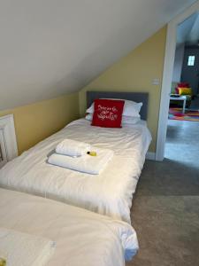 1 dormitorio con 2 camas, toallas y almohada roja en Ashbrook House Apartments, en Dungannon