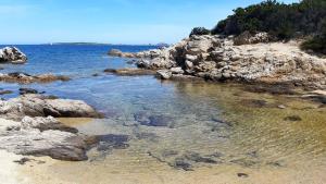 a beach with rocks and the ocean on a sunny day at Casanuova Flat, City Center in Olbia