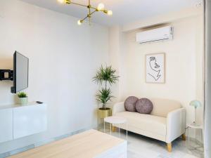 a living room with a white couch and a tv at Alora Home - Hostatel in Cenes de la Vega