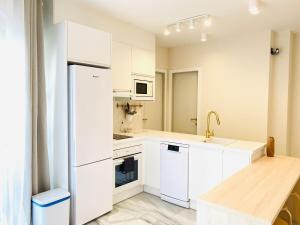 a kitchen with white cabinets and a white refrigerator at Alora Home - Hostatel in Cenes de la Vega
