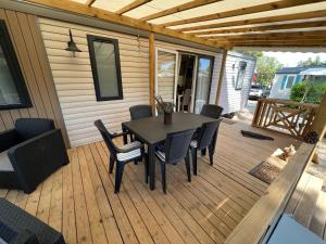 a patio with a table and chairs on a deck at Mobil home Petit Paradis, 6 personnes, Bord de mer, Camping Del Mar Village in Argelès-sur-Mer