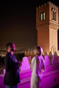un hombre y una mujer parados frente a una torre del reloj en Palazzo Vecchio Taormina, en Taormina