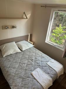 a bedroom with a bed with two pillows and a window at MobilHome 3 chambres 6 personnes Piscine Camping Saint Cheron in Saint-Chéron