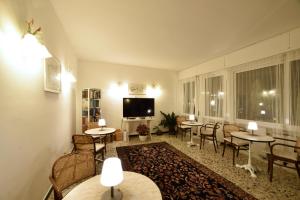 Hotel Villa Giulia في لايقويليا: غرفة معيشة مع طاولات وكراسي وتلفزيون بشاشة مسطحة