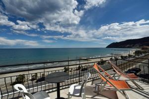 a balcony with chairs and a table and the beach at Hotel Villa Giulia in Laigueglia