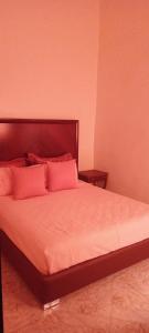 una camera da letto con un grande letto con cuscini rosa di Dar abd essalam a Moulay Yacoub