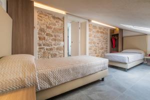 a bedroom with two beds and a stone wall at Goloritzè Room and Breakfast in Baunei