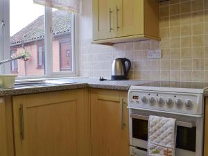 cocina con fogones, fregadero y ventana en Stable Cottage 5 - Ukc3744, en Bawdeswell