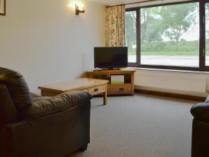 sala de estar con TV, sofá y mesa en Stable Cottage 5 - Ukc3744, en Bawdeswell