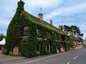 an ivy covered building on the side of a street at The Wheatsheaf Inn in Bourton on the Water