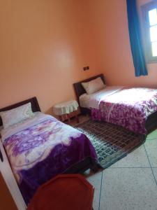 1 dormitorio con 2 camas, mesa y ventana en Chez L'habitant Brahim kanih 