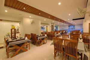 a restaurant with wooden tables and chairs in a room at Hotel NovArk Munnar in Kallar Vattiyar