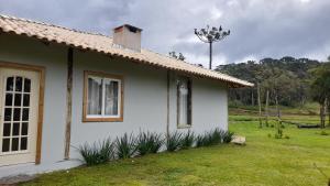 a white house with a window and a grass yard at Refúgio Altos do Campestre - TURISMO RURAL in Urubici