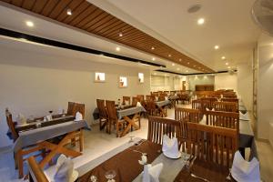 a restaurant with wooden tables and chairs in a room at Hotel NovArk Munnar in Kallar Vattiyar