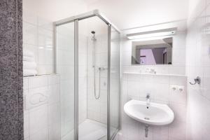 a white bathroom with a sink and a shower at Firzlaff's Hotel in Neumünster