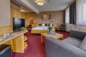 a hotel room with a bed and a flat screen tv at Kurpension Freudenstein in Bad Füssing