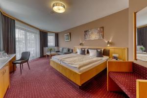 a hotel room with a large bed and a desk at Kurpension Freudenstein in Bad Füssing