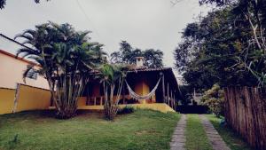 a house with palm trees and a hammock in the yard at PENEDO COM 4 QUARTOS, PISCINA E SAUNA. 600M do CENTRO in Penedo