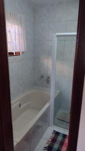 a white bathroom with a tub and a shower at PENEDO COM 4 QUARTOS, PISCINA E SAUNA. 600M do CENTRO in Penedo +8 photos