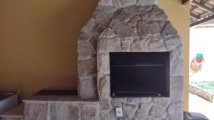 a stone fireplace with a tv in a room at PENEDO COM 4 QUARTOS, PISCINA E SAUNA. 600M do CENTRO in Penedo