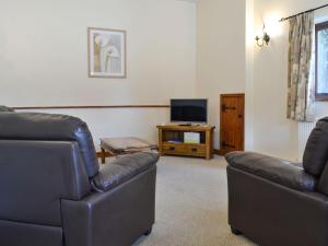 een woonkamer met 2 banken en een televisie bij Pond Cottage - Ukc3736 in Bawdeswell
