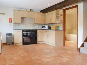 una cocina con armarios de madera y electrodomésticos negros en Pond Cottage - Ukc3736, en Bawdeswell