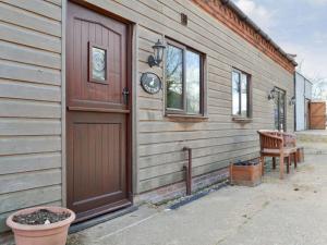 a house with a wooden door and a window at Pond Cottage - Ukc3736 in Bawdeswell