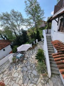 patio z ławką, parasolem i schodami w obiekcie Kapsala's family HOME w mieście Agios Ioannis Pelio