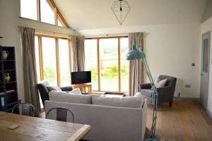 een woonkamer met een bank, stoelen en een lamp bij River Cottage - Stunning estuary views in Aldeburgh