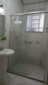 a shower with a glass door next to a sink at Alzira Plaza Hotel in São Lourenço