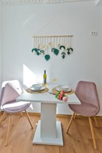 ein Esszimmer mit einem weißen Tisch und 2 rosafarbenen Stühlen in der Unterkunft *Beautiful, centrally located studio apartment* in Hvar