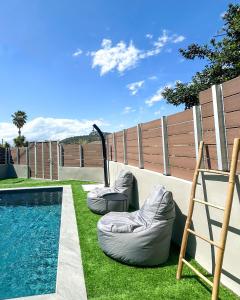 une arrière-cour avec deux poufs à côté d'une piscine dans l'établissement Piedra Luxury Apartments, à Nauplie