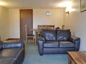 a living room with a leather couch and a table at Stable Cottage 6 - Ukc3745 in Bawdeswell