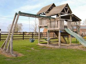 a wooden playground with a slide and swings at Stable Cottage 6 - Ukc3745 in Bawdeswell