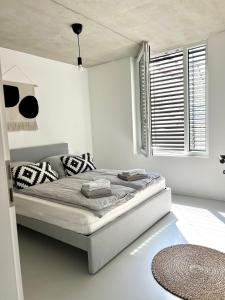a white bedroom with a bed with pillows and a window at Weinberg-Design-Apartment Stuttgart-Fellbach in Fellbach