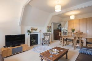 a living room with a television and a dining room at Spacious 3BR Victorian Cheltenham loft flat in Cotswolds Sleeps 8 - FREE Parking in Cheltenham