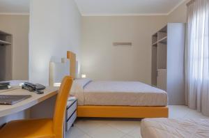 a bedroom with a bed and a desk with a computer at Ghibli Hotel in San Vito lo Capo