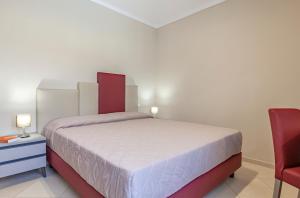 a bedroom with a bed and a red chair at Ghibli Hotel in San Vito lo Capo