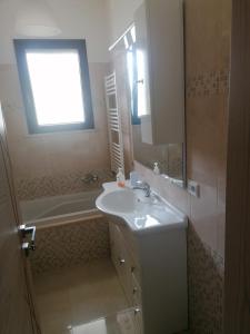a bathroom with a sink and a tub and a window at Albachiara in Galatina