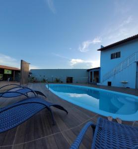 a swimming pool with two chairs and a building at POUSADA ALÉM-K in Riachão