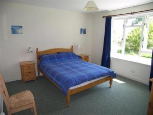una camera da letto con un letto con un piumone blu e una finestra di Glenauld Cottage a Kirkcudbright Altre 18 foto