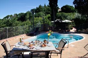 a table with food on it next to a pool at Antica Pietra holiday house with pool in Montaione