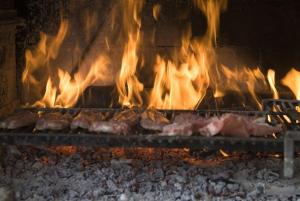 un montón de carne cocinando en un horno con llamas en Rifugio Montano, en Orsomarso