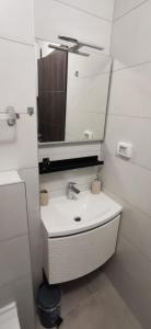 a white bathroom with a sink and a mirror at Apartment Sandy Beach - 1st row at sea in Pješčana Uvala 